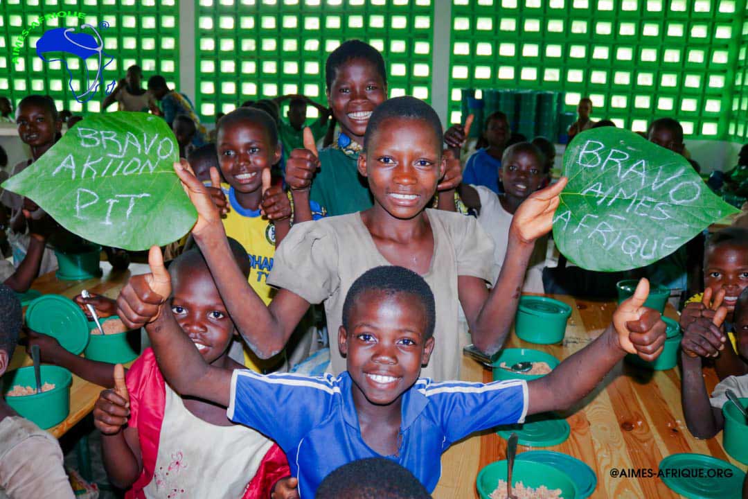 Lachende KiSS-Kinder halten Blätter mit Bravo Aktion PiT und Bravo Aimes-Afrique in den Händen