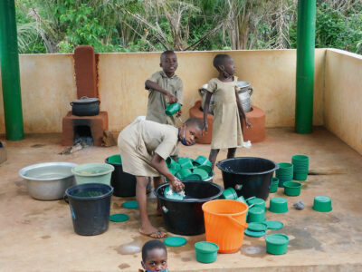 Kinder beim Abwaschen ihrer Teller und Becher