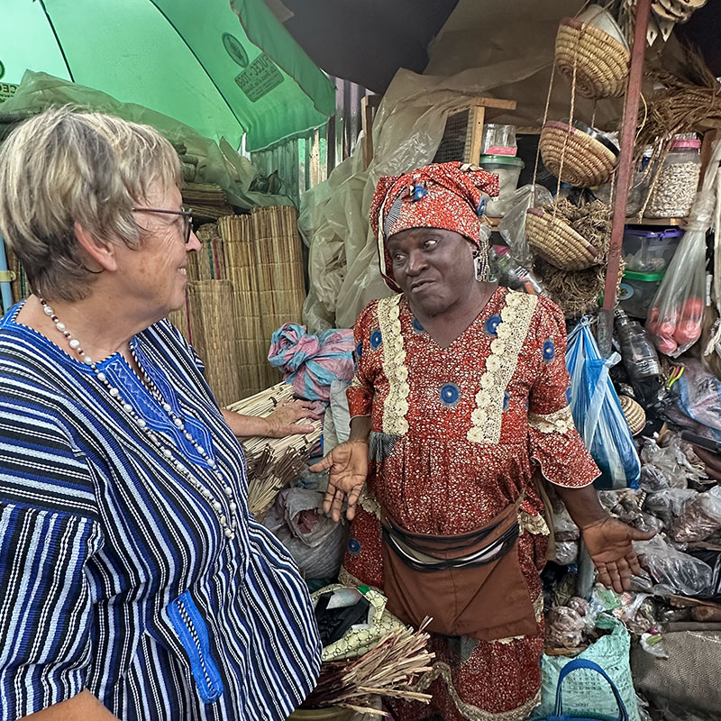 Eine Marktfrau an ihrem Stand im Gespräch mit Margret Kopp