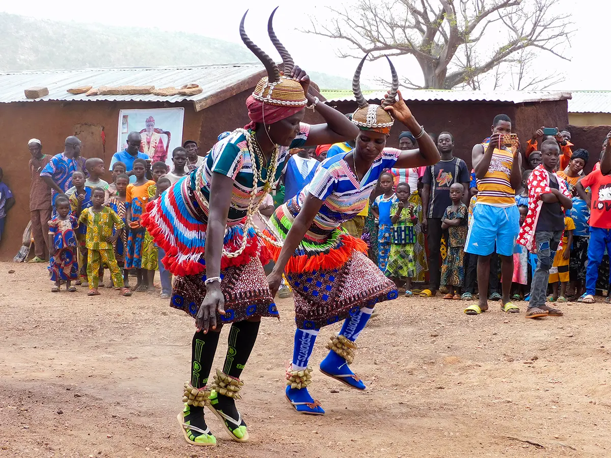 Zwei Frauen tanzen einen traditionellen Tanz mit Hörner-Masken auf dem Kopf
